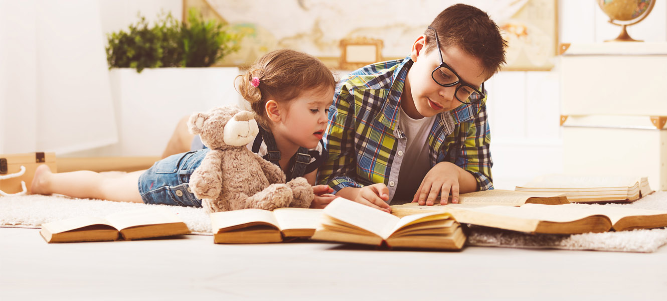 A brother reading a book to his little sister.